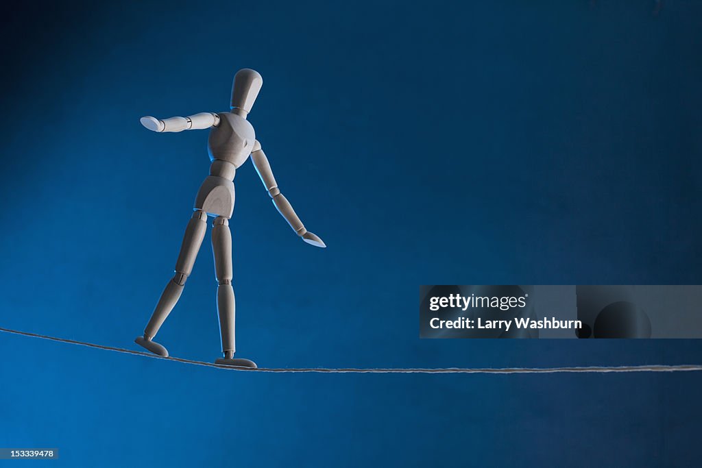 An artist's figure walking a tightrope