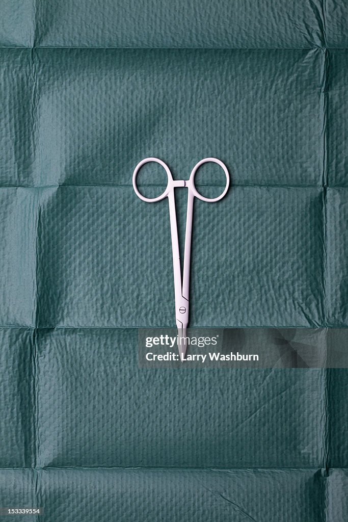 A pair of surgical scissors on a surgical drape