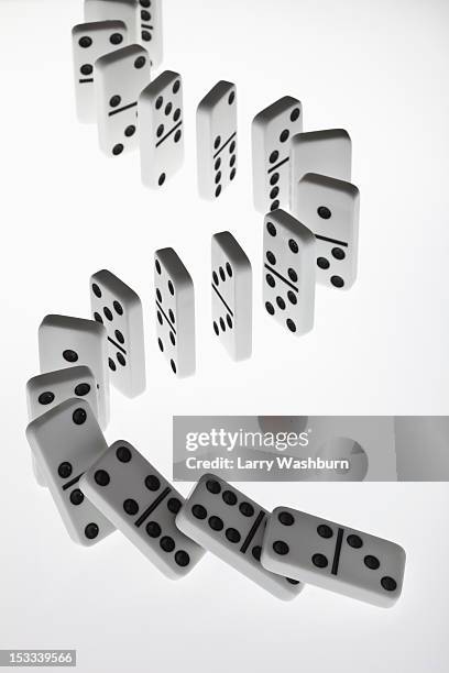 dominoes in a row, beginning to fall over in a chain reaction - dominos falling stock pictures, royalty-free photos & images