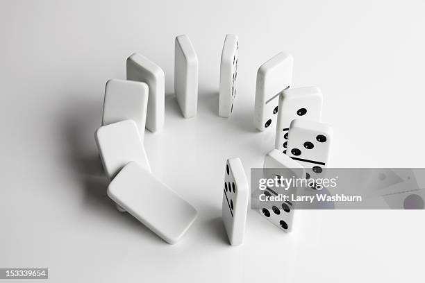 dominoes in a circle beginning to fall over in a chain reaction - dominostein stock-fotos und bilder