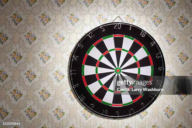 a dartboard hanging on a wallpapered wall - cible de jeu de fléchettes photos et images de collection