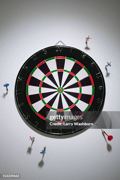darts stuck in a wall all around a dartboard - alvo de dardo imagens e fotografias de stock