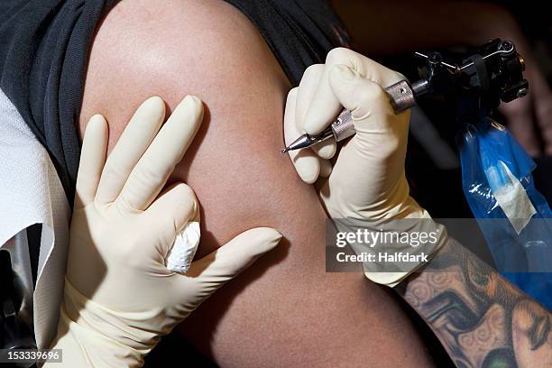 a tattoo artist preparing to tattoo a man's bare arm, close-up - tatuaje fotografías e imágenes de stock