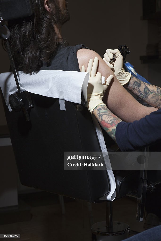 A tattoo artist preparing to tattoo a man's bare arm