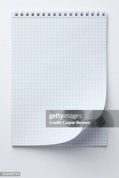 a spiral notepad with graph paper and a curled up page corner - ruitjespapier stockfoto's en -beelden