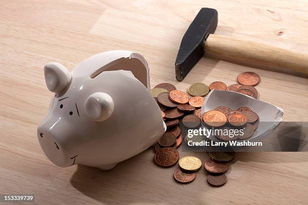 a hammer lying next to a broken piggy bank with euro coins spilling out - smashed piggy bank stock pictures, royalty-free photos & images