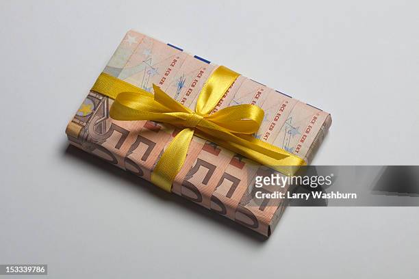 fifty euro banknotes used to wrap a gift with a yellow bow - vrijgevigheid stockfoto's en -beelden