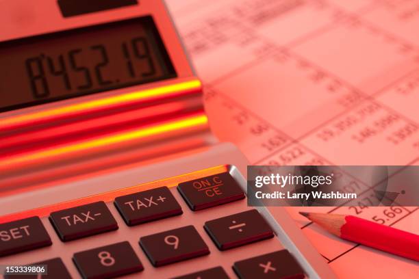 a calculator on a financial document illuminated in red light - burocrazia foto e immagini stock