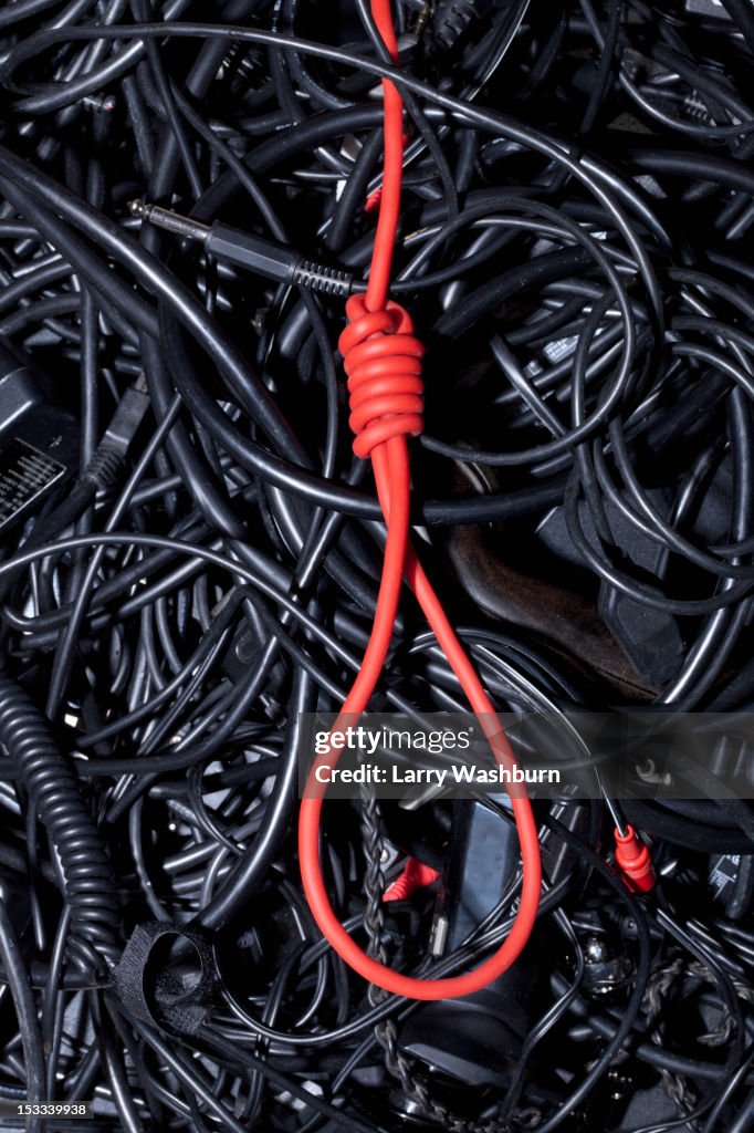 A red cord tied into a noose amongst tangled black cables and cords