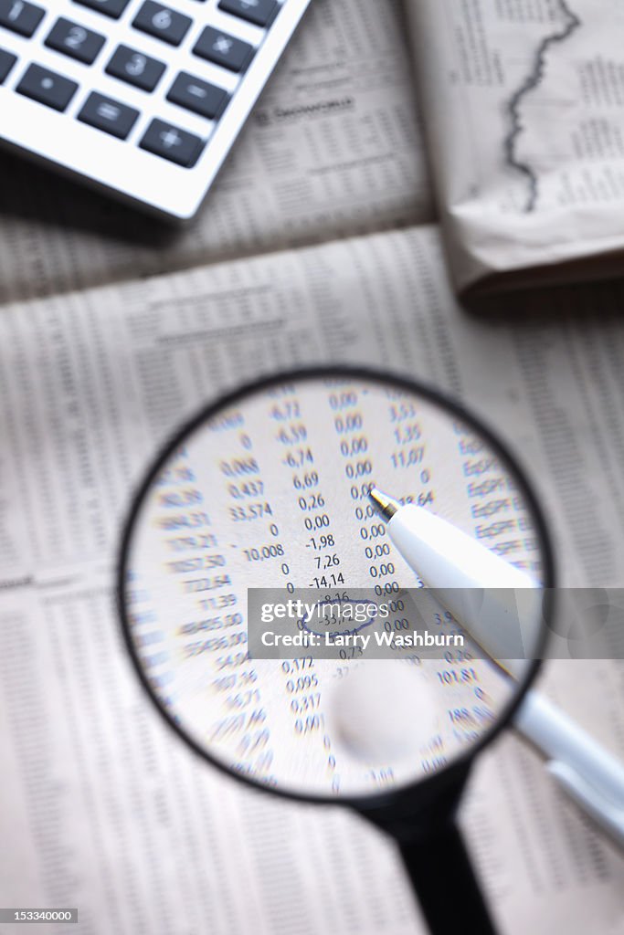 A magnifying glass magnifying a circled figure on a financial page