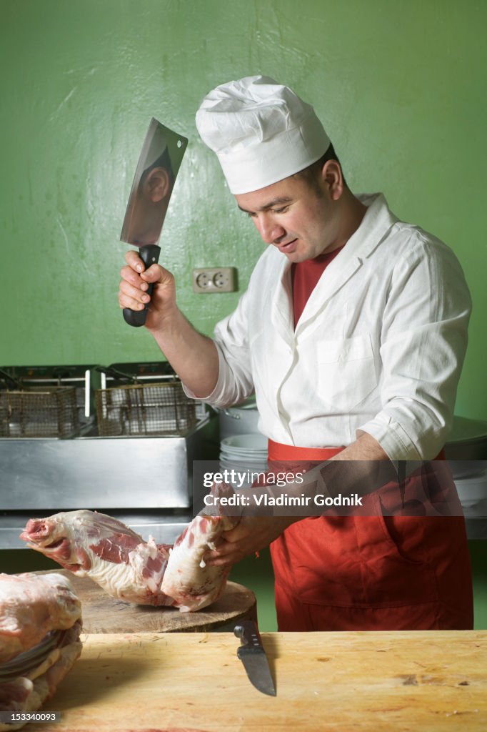 A butcher chopping meat with a cleaver