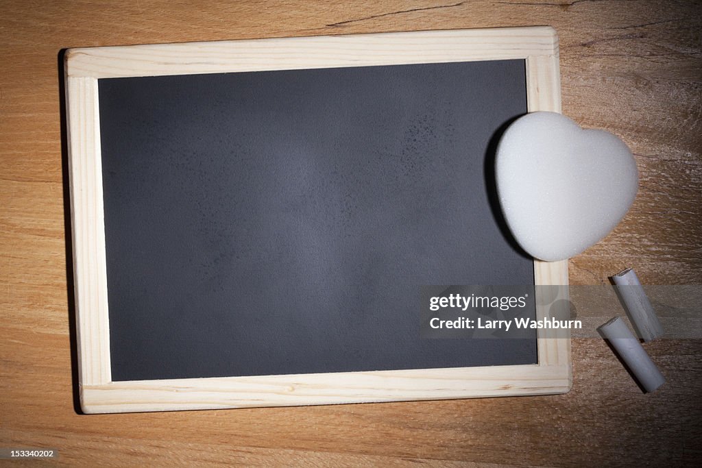 A small blank chalkboard with chalk and a heart shaped eraser