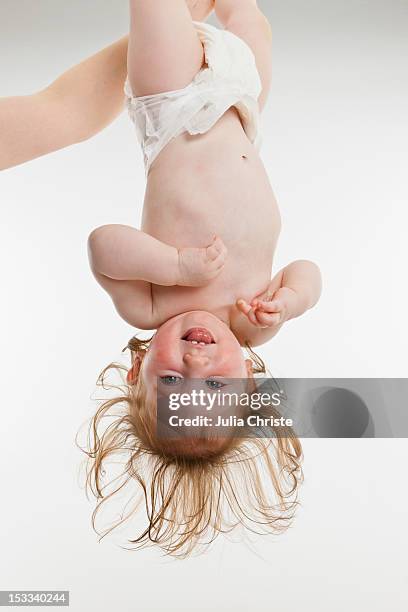 a baby girl held upside down - baby studio bildbanksfoton och bilder