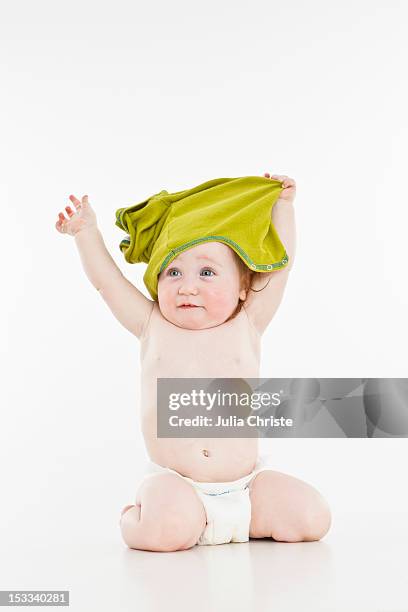 a baby girl pulling her shirt off - babys take in their diapers off stock pictures, royalty-free photos & images