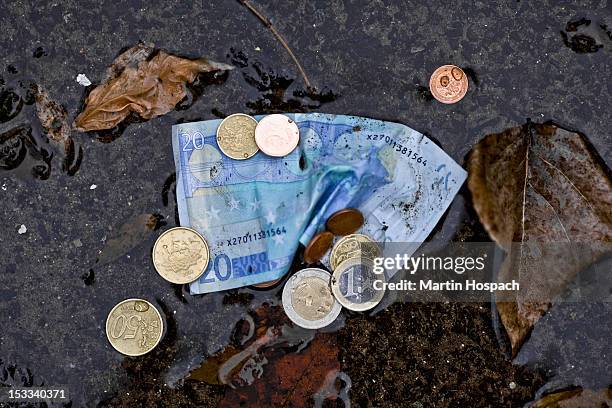 a twenty euro banknote and euro coins in a puddle - moeda de um euro imagens e fotografias de stock