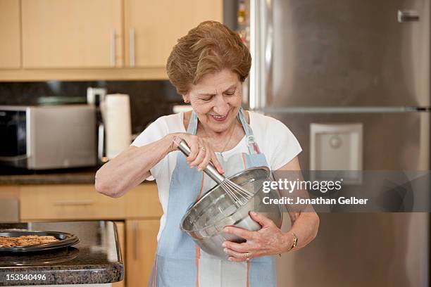 a senior woman mixing ingredients in a bowl - whipping woman stock pictures, royalty-free photos & images