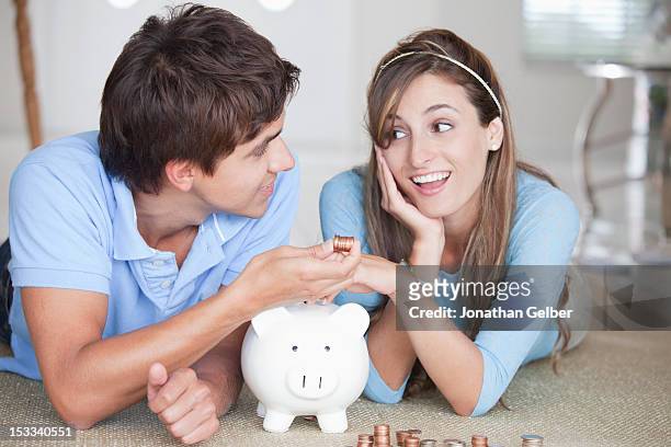 a young couple lying on the floor counting coins - couple saving piggy bank stock pictures, royalty-free photos & images
