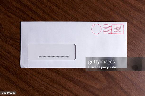 a window envelope with no address, but a barcode and red ink postage stamp - busta foto e immagini stock