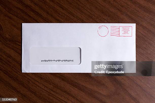 a window envelope with no address, but a barcode and red ink postage stamp - envelope stockfoto's en -beelden