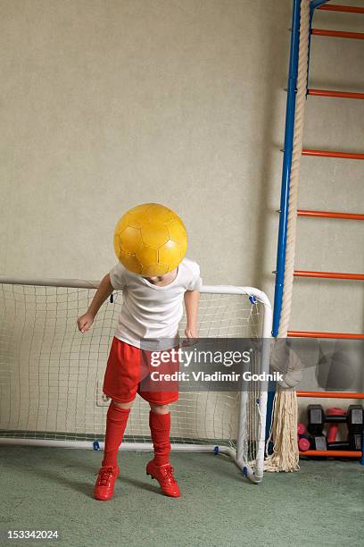 a young boy jumping to head butt a soccer ball away from a goal - boy goalie standing in front of goal net stock pictures, royalty-free photos & images