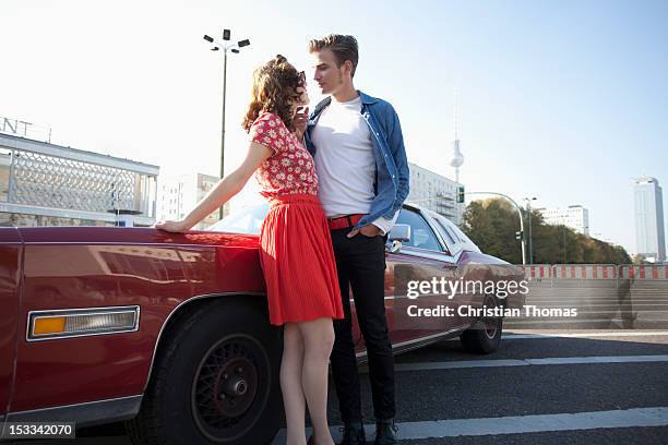 a flirtatious rockabilly couple standing next to a vintage car, berlin, germany - rockabilly pin up girls stock pictures, royalty-free photos & images