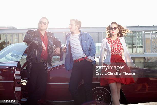 three rockabilly friends leaning against a vintage car - rockabilly pin up girls stock pictures, royalty-free photos & images