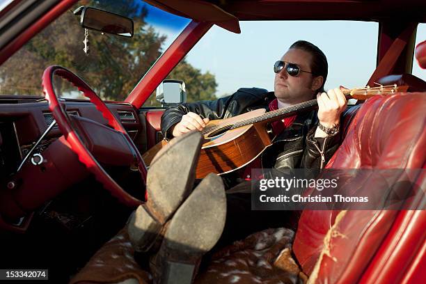 a rockabilly guy playing an acoustic guitar while sitting in his vintage car - 50s rockabilly men stock pictures, royalty-free photos & images