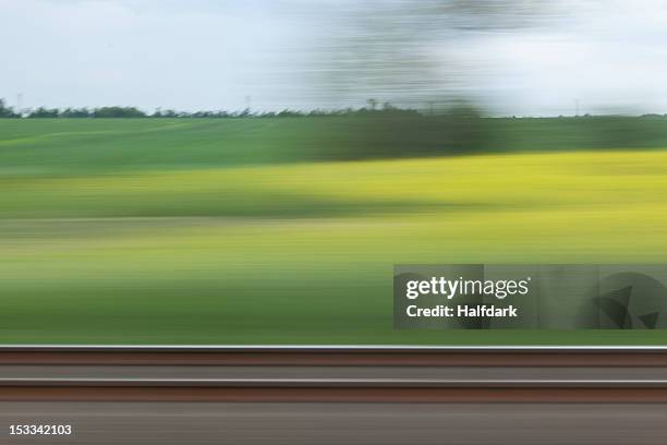 a rural landscape in blurred motion viewed from a moving train - railroad track stock-fotos und bilder