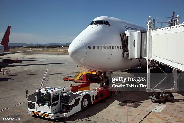 jumbo jet attached to boarding bridge with tug in front - aéroport kingsford smith photos et images de collection