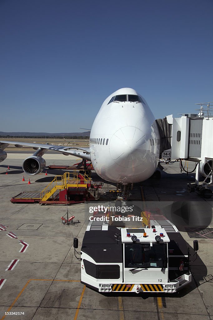 Jumbo jet attached to boarding bridge with tug in front