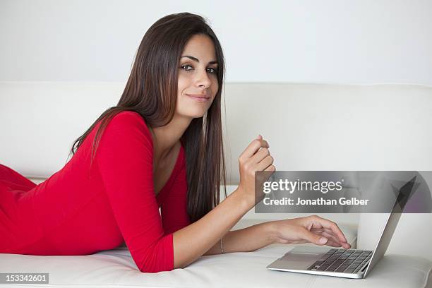 woman in red on sofa with laptop - leaning on elbows stock pictures, royalty-free photos & images