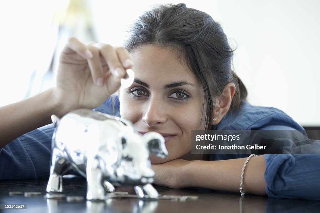 Woman putting coin into piggy bank