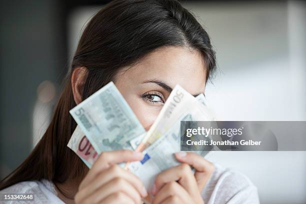woman peeking behind euro notes - euroscheine stock-fotos und bilder