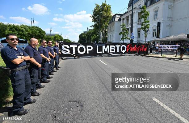 Police officers stand by as members of the far-right 'The Hungarian self-defence movement' protest against the LGBTQ+ Pride Parade in Budapest,...