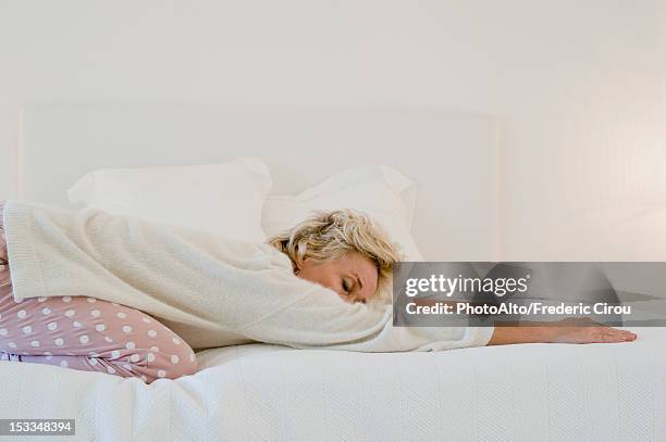 mature woman doing child's pose on bed - yoga kissen stock-fotos und bilder