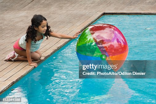 Pool Crounching Girl Crouching Beside Pool Playing With Beach Ball Photo - Getty Images
