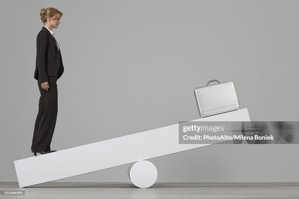 Businesswoman balancing on seesaw