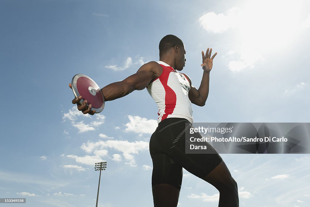 Male athlete throwing discus, low angle view