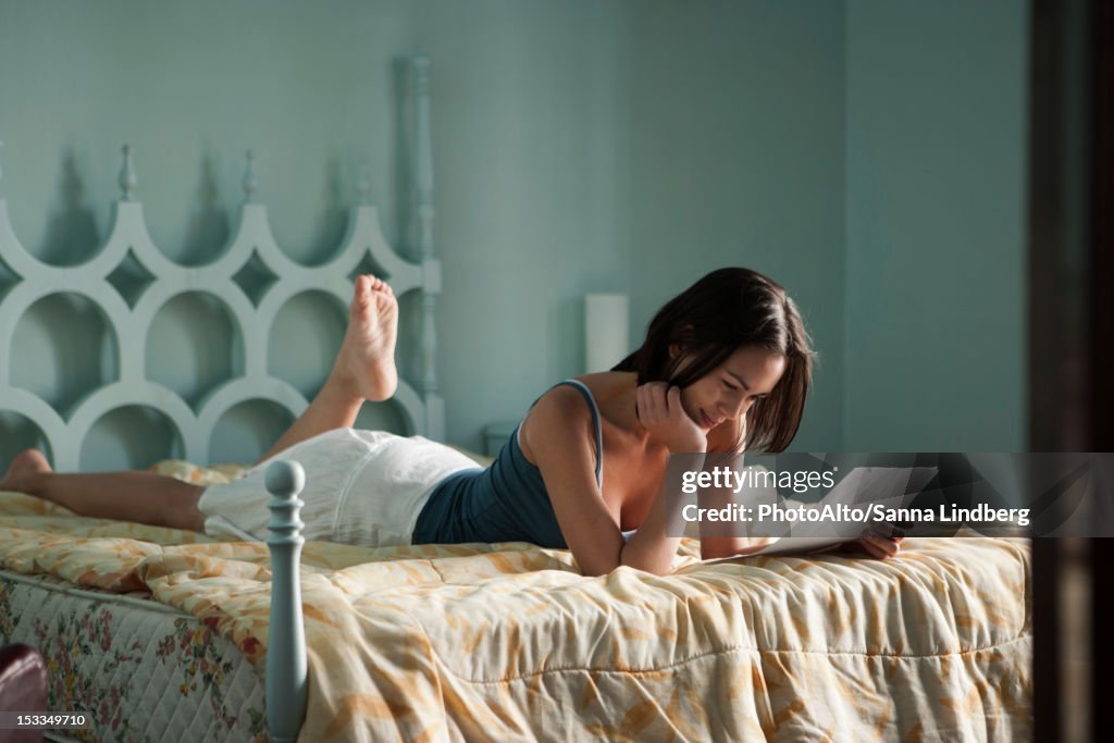 Woman lying on bed, reading letter