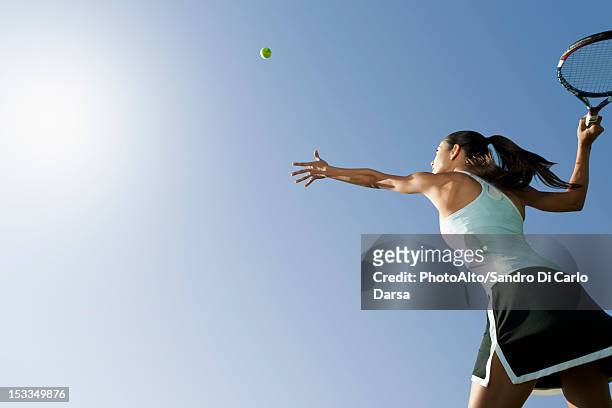 female tennis player serving ball, low angle view - tennis stock-fotos und bilder