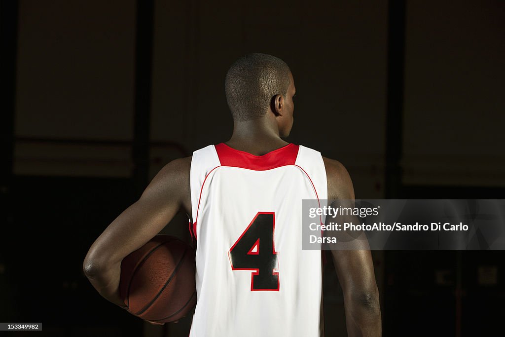 Basketball player holding basketball, rear view