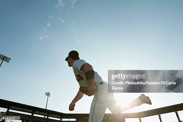 baseball pitcher throwing pitch, backlit - pitcher di baseball fotografías e imágenes de stock