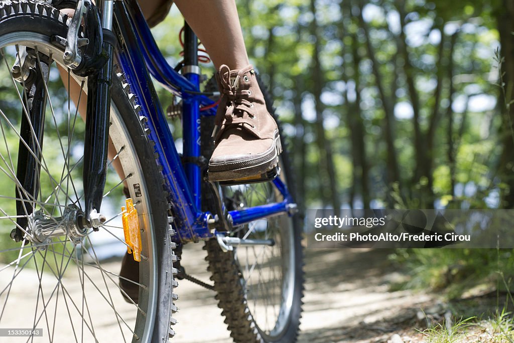 Woman riding bicycle through woods