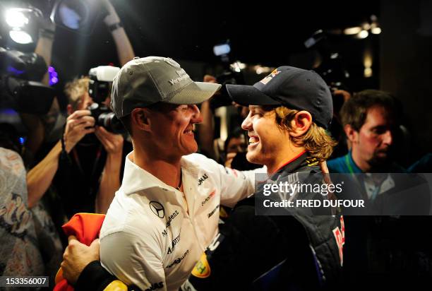 Red Bull's German driver Sebastian Vettel is congratulated by Mercedes GP's German driver Michael Schumacher with his team members at the Yas Marina...