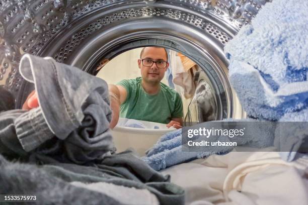 mittlerer erwachsener mann, der wäsche aus der waschmaschine nimmt - blick durch kameraobjektiv stock-fotos und bilder