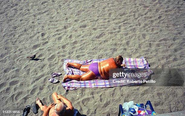 Fat woman taking sunburn at beach in Napoli, Italy.