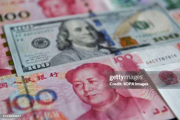 In this photo illustration, several 100 yuan banknotes and 100 US dollar banknote seen placed on a table.