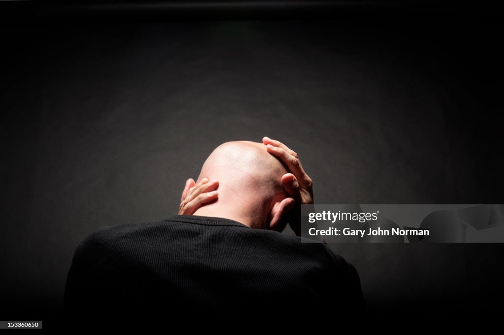 Man holding head in hands rear view