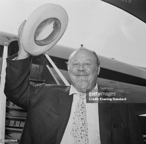 American singer and actor Burl Ives waves his hat after after arriving at London Airport, June 11th 1959.