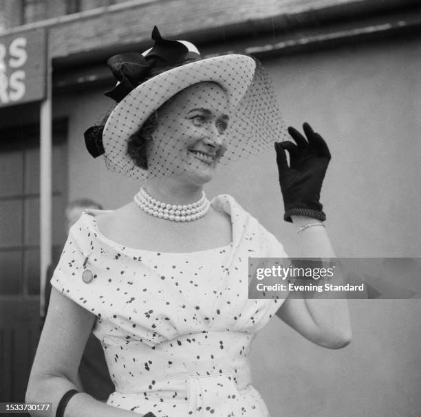 Woman holds the veil of her fascinator hat during Oaks Day, Epsom Derby, Surrey, June 5th 1959.